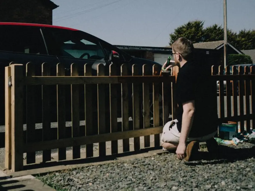 Person painting a wooden fence with a brush